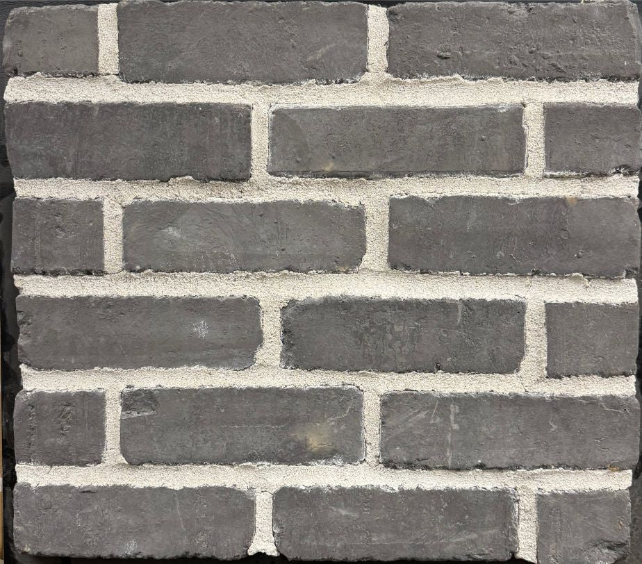 Brick – Charcoal sample board. Deep charcoal gray brick with a lightly weathered face, shown with a light gray mortar joint.