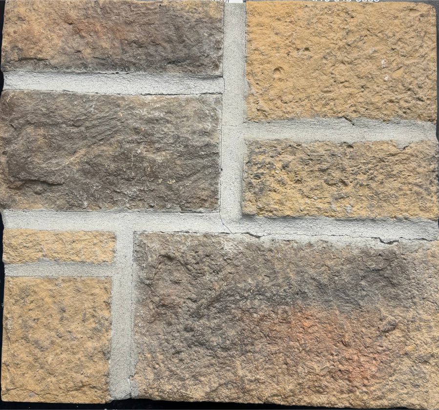 Castle – Walnut sample board. A blend of golden tan and brown-gray blocks with a rough face, shown with a gray mortar joint.