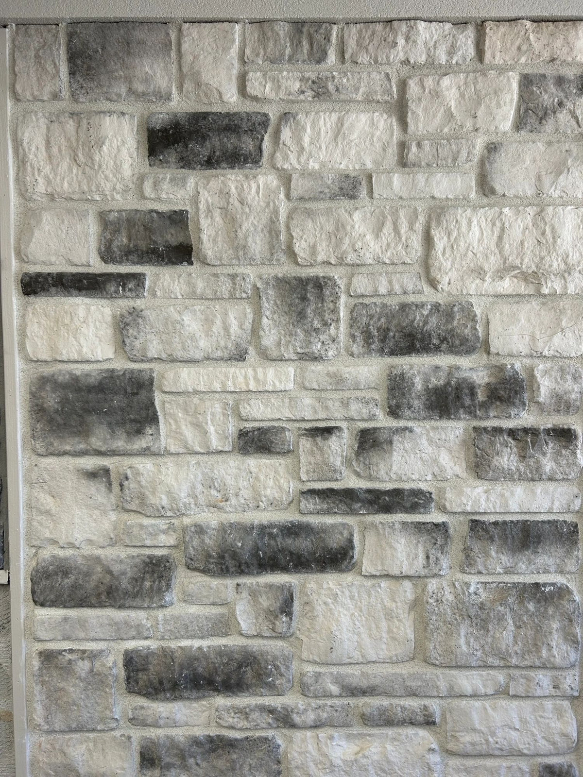 Tumbled manufactured stone veneer, Snow with Charcoal, installed